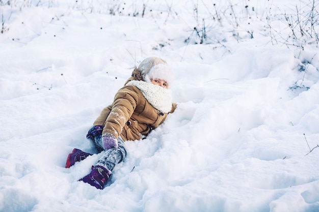 Funny little girl lying in the winter in the snow