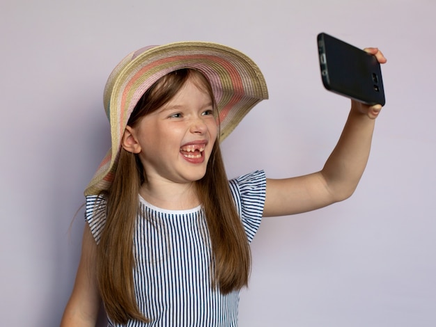 Photo funny little girl makes selfie by smartphone