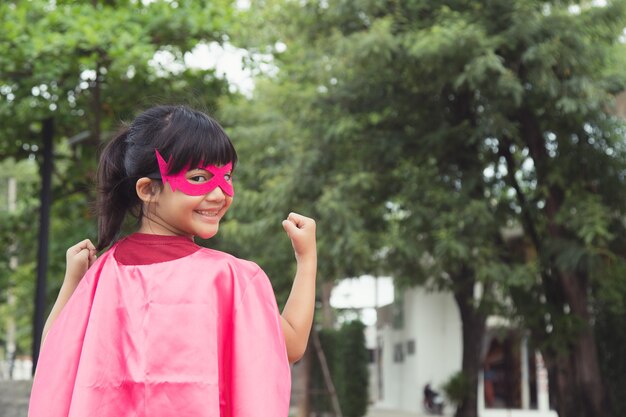 Funny little girl playing power superhero over white background. superhero concept.