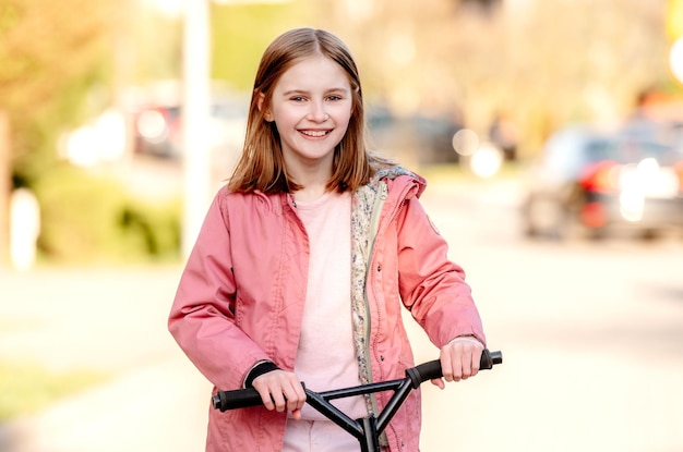 Funny little girl rides a kick scooter