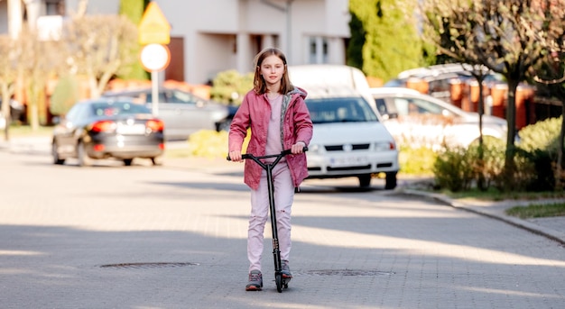 Funny little girl rides a kick scooter