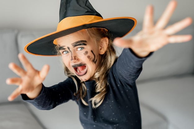 Foto bambina divertente che indossa il costume e il trucco del cappello della strega bambino felice in costume di halloween pronto per la festa di halloween