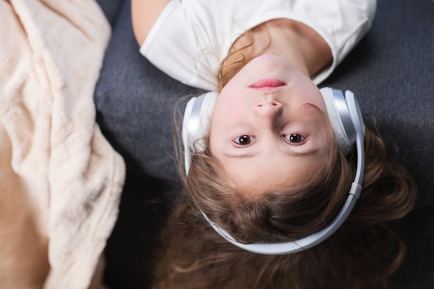 Bambina divertente in cuffie senza fili che ballano cantando e muovendosi al ritmo. cuffie da portare della bambina. capretto in cuffia. bambina felice che ascolta la musica con le cuffie.