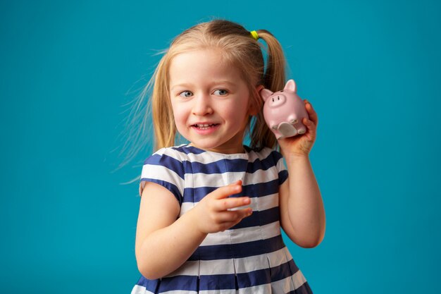 Funny little girl with piggy bank