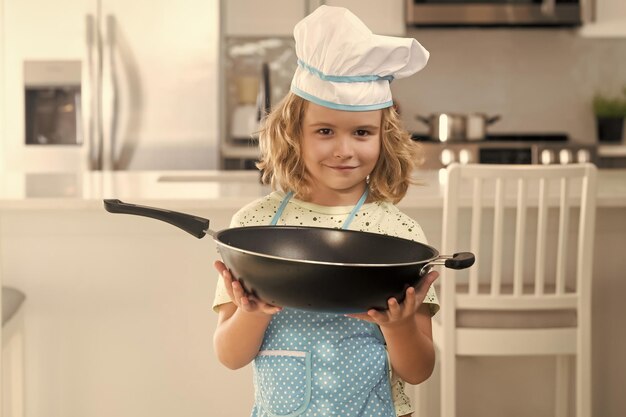 Foto strano bambino cuoco cuoco che indossa l'uniforme cuoco cappello e grembiule cotto cibo in cucina i bambini stanno preparando l'impasto cucinare biscotti in cucina