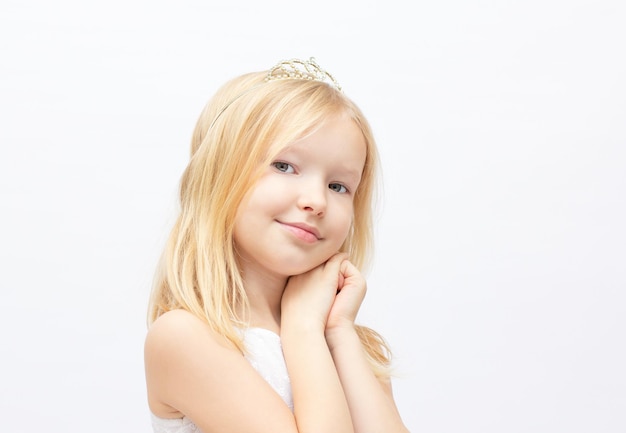 Funny little princess girl in silver crown and white dress over white background