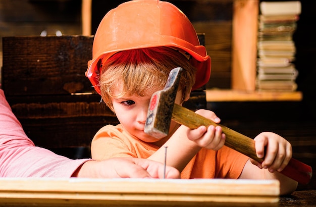 Funny little repairman with hammer kids construction worker child use a hammer to nail