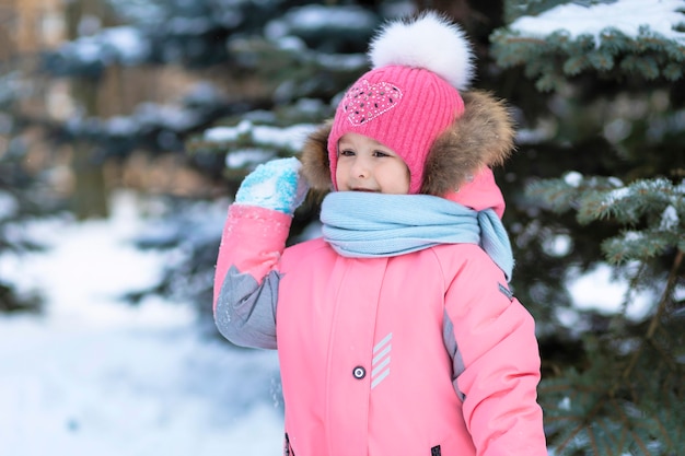 Funny little toddler girl playing in snowballs. wintertime, winter game for children. kid having fun christmas time