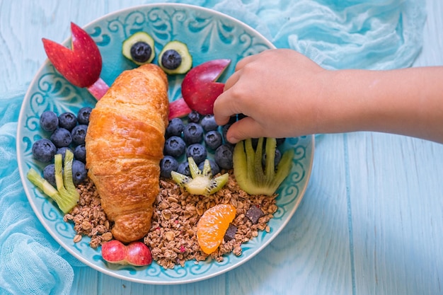 Croissant all'aragosta divertente con frutti di bosco per la colazione dei bambini