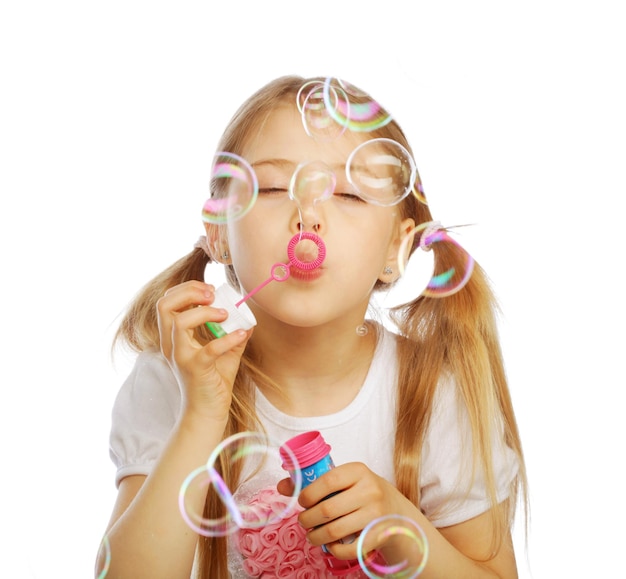 Забавная милая маленькая девочка дует мыльные пузыри