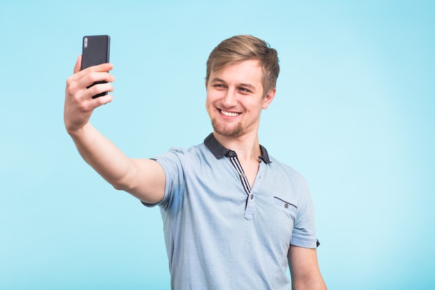 Funny man grimacing while making selfie on blue