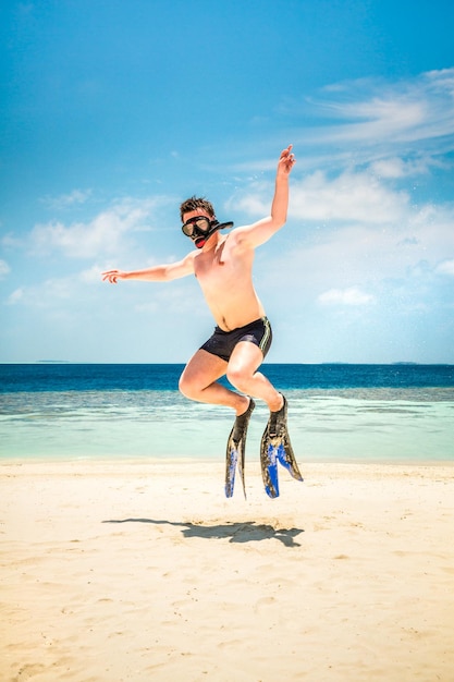Смешной человек прыгает в ластах и маске. Праздничные каникулы на тропическом пляже на Мальдивских островах.