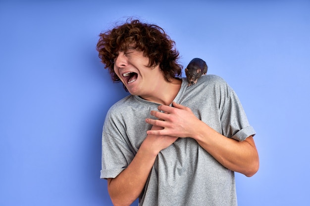 Funny man at a loss, does not know what to do with a rat on his t-shirt, grimace, make face