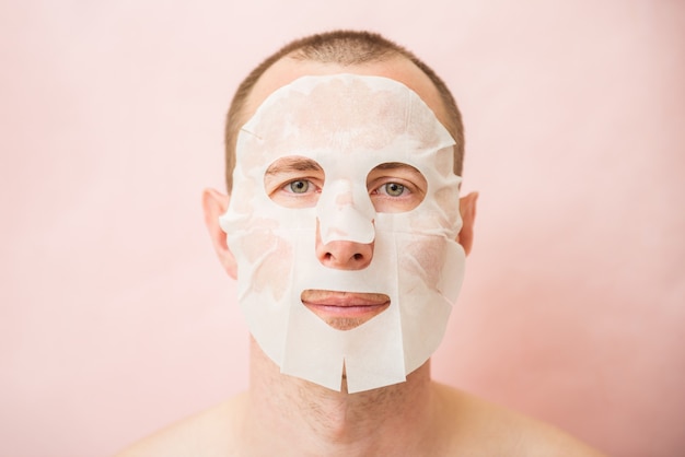 Funny man receiving nourishing facial mask.