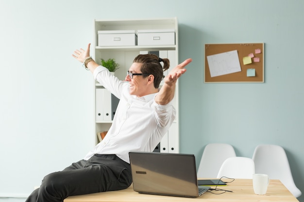 Funny man in white shirt sitting on wooden table in office