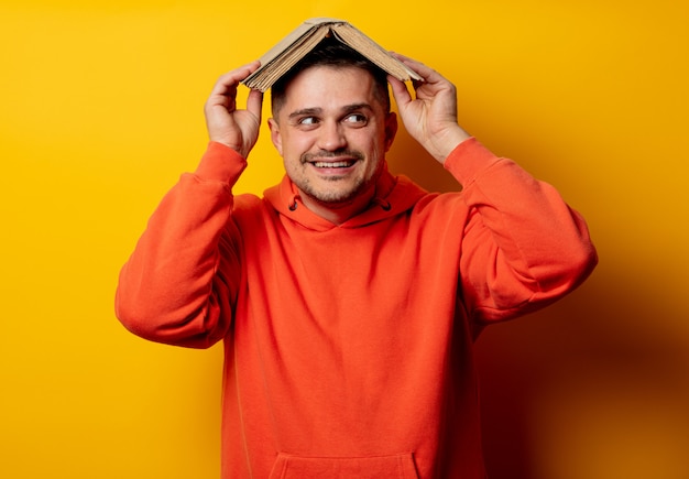 Funny man with book on head on yellow wall