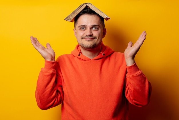 Funny man with book on head on yellow wall