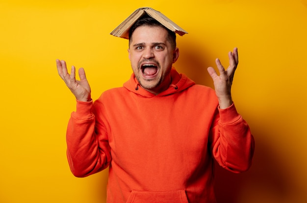 Funny man with book on head on yellow wall