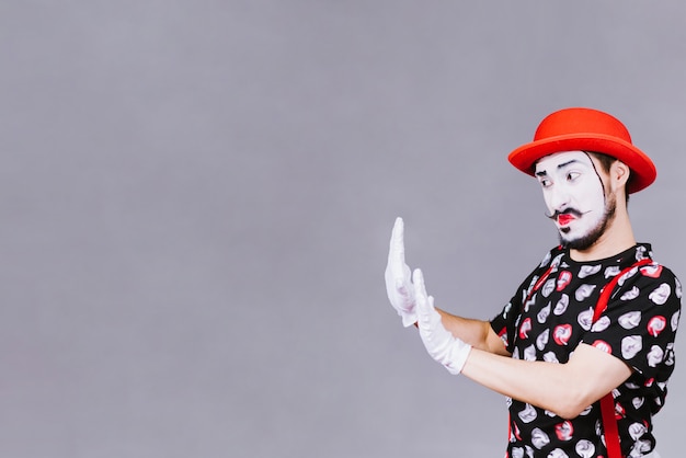 Funny mime posing near a gray 