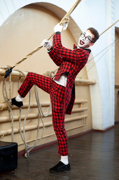 Funny mime in a red suit pulls a rope