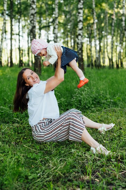 Funny mom with baby sitting on the grass