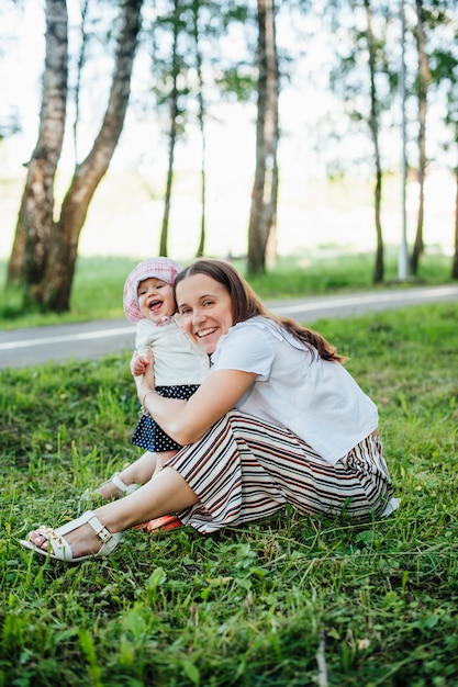 Funny mom with baby sitting on the grass