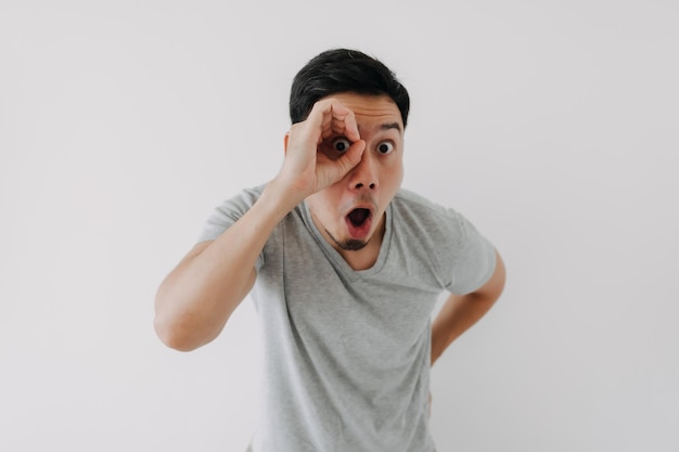 Funny obvious peeking man in grey tshirt isolated on white background