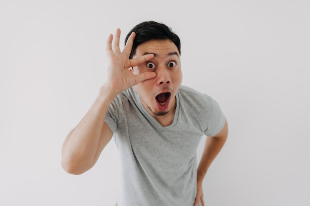 Funny obvious peeking man in grey tshirt isolated on white background