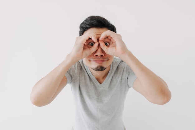 Funny obvious peeking man in grey tshirt isolated on white background