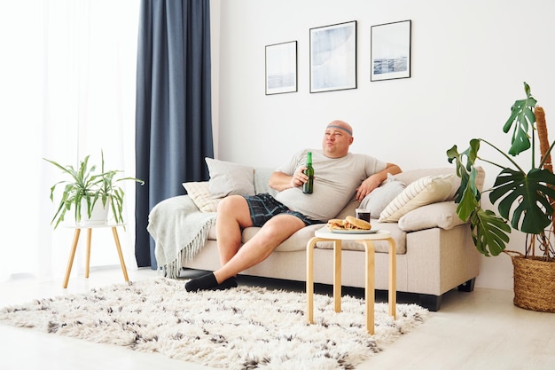 Funny overweight man in casual clothes is indoors at home