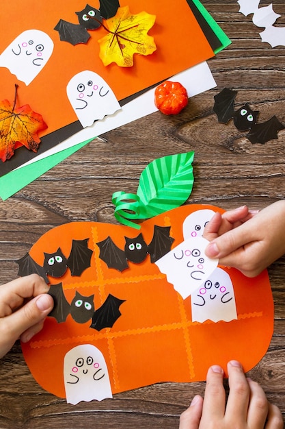 Funny paper toy in the form of a Halloween pumpkin on a wooden table Childrens art project