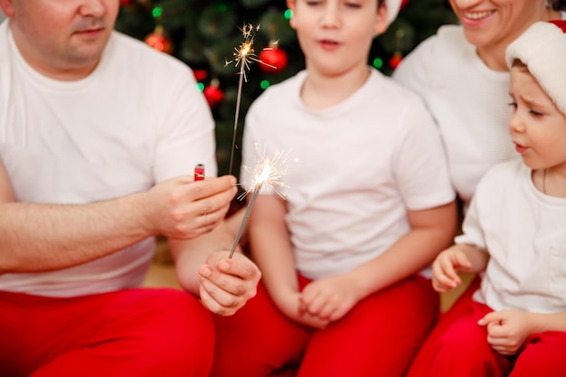 Funny parents and children on Xmas with burning sparklers at home