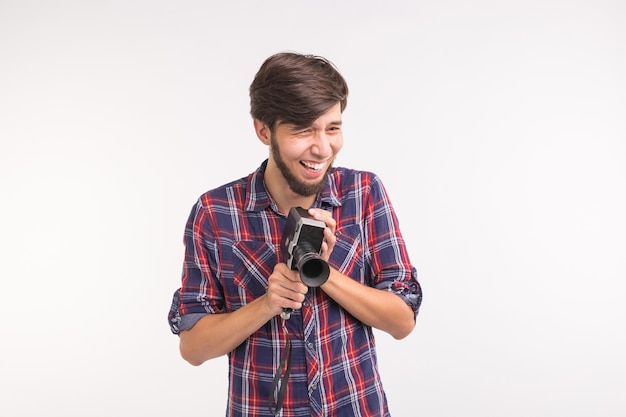 Persone divertenti, foto e concetto vintage - giovane che usa la macchina fotografica vintage su sfondo bianco