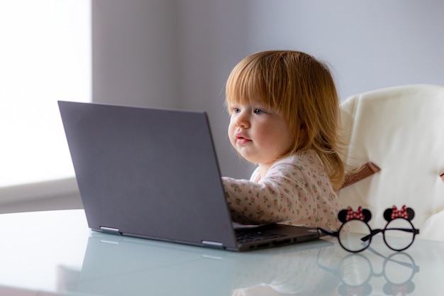 Funny photo -  baby with laptop on remote work, learning