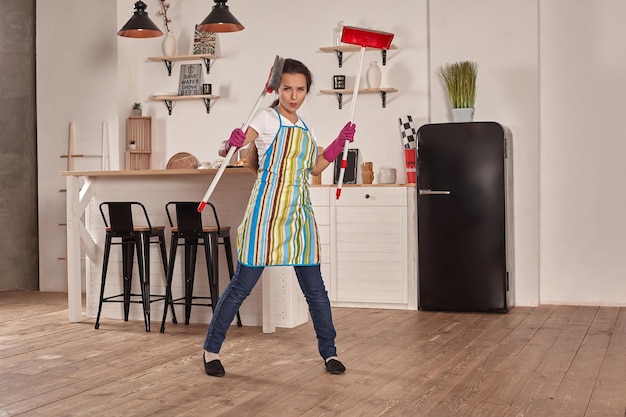 Funny picture of brunette holding scoop and broom in hands she pretends it is swords girl is ready f...