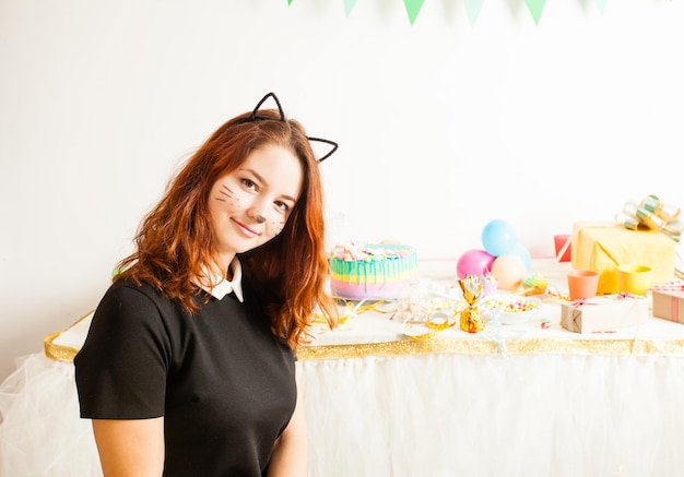 Funny playful girl animator in costume of cat holding colorful balls on the birthday party