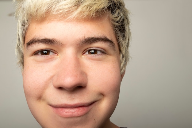 Funny portrait of teenage boy close up with small smile