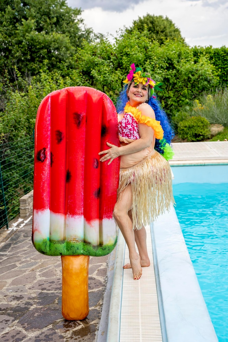 Photo funny portrait of woman dressed in hawaiian costume near inflatable ice cream mattress by the pool