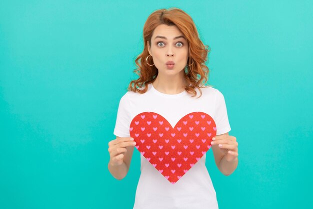 Funny redhead woman hold red heart on blue background