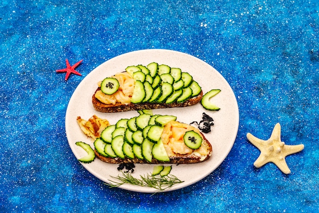 Funny salmon sandwiches with cucumber in fish shape