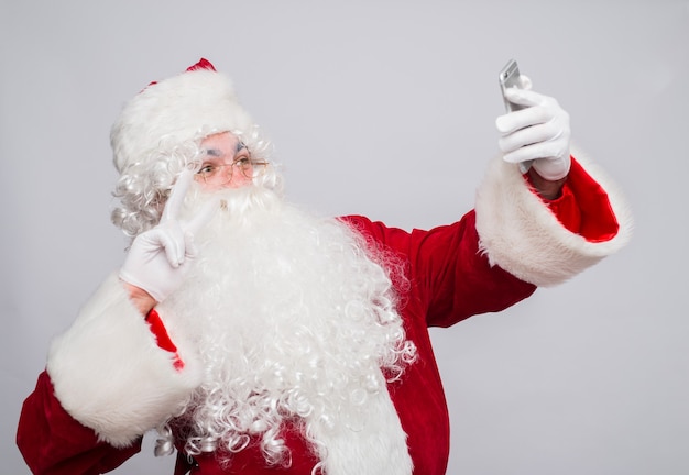 Foto babbo natale divertente in un costume rosso con un telefono