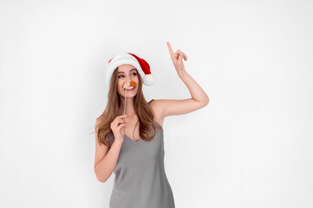 Funny santa girl wears pretend mustache raises up hand with index finger new year advertisement