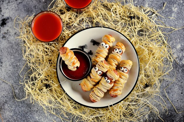 Divertenti mummie di salsiccia nell'impasto con ketchup per la festa di halloween