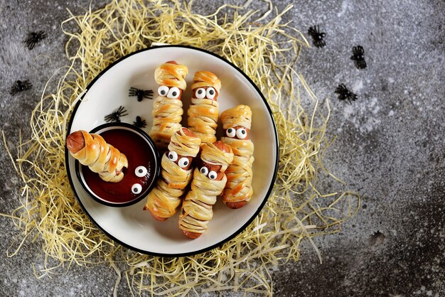 Divertenti mummie di salsiccia nell'impasto con ketchup per la festa di halloween