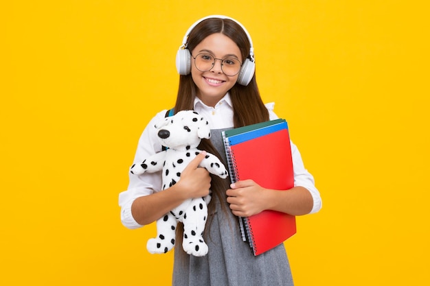 Funny school girl with toy isolated on yellow background Happy childhood and kids education Happy schoolgirl positive and smiling emotions