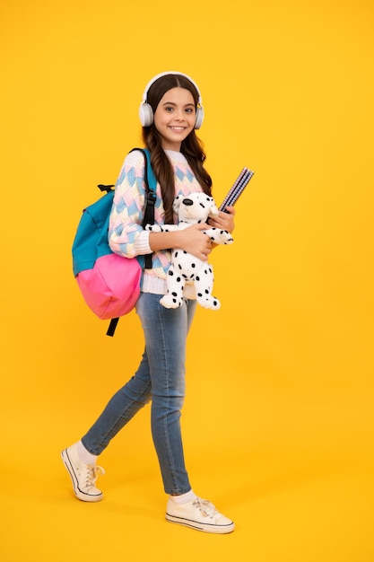 Funny school girl with toy isolated on yellow background Happy childhood and kids education