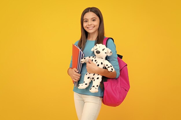 Funny school girl with toy isolated on yellow background Happy childhood and kids education