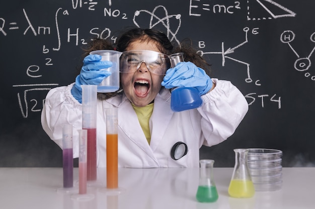 Funny scientist girl in lab coat with flasks