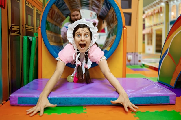 Donna urlante divertente che indossa come neonato nel labirinto al centro ricreativo per bambini