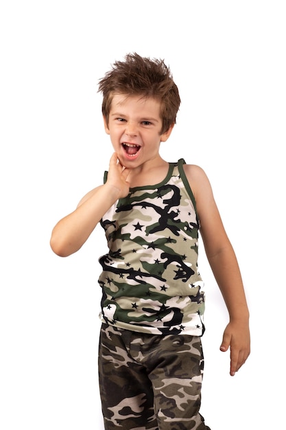 Смешной лохматый мальчик в красочной футболке цвета хаки и шортах удивлен и кричит